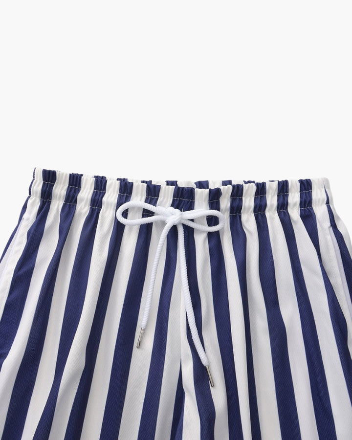 Uomo che indossa pantaloncini da bagno a righe, ideali per nuoto, spiaggia e sport acquatici. Asciugatura rapida.