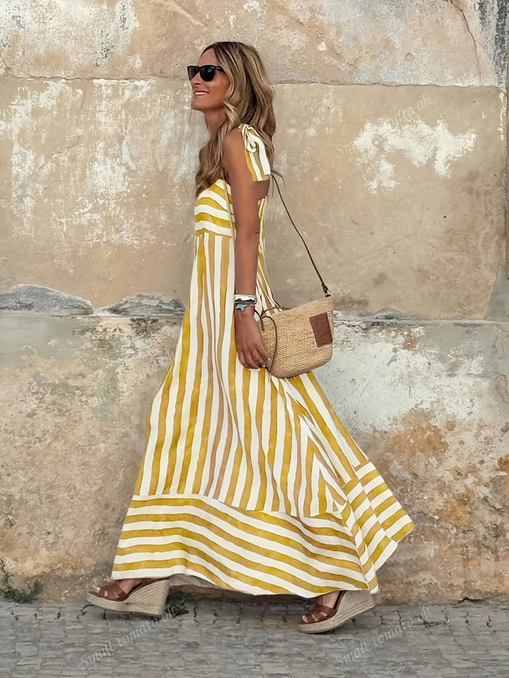 Chic abito maxi da donna a righe bianche e blu, con spalline. Look estivo fluido e versatile, ideale per ogni occasione.