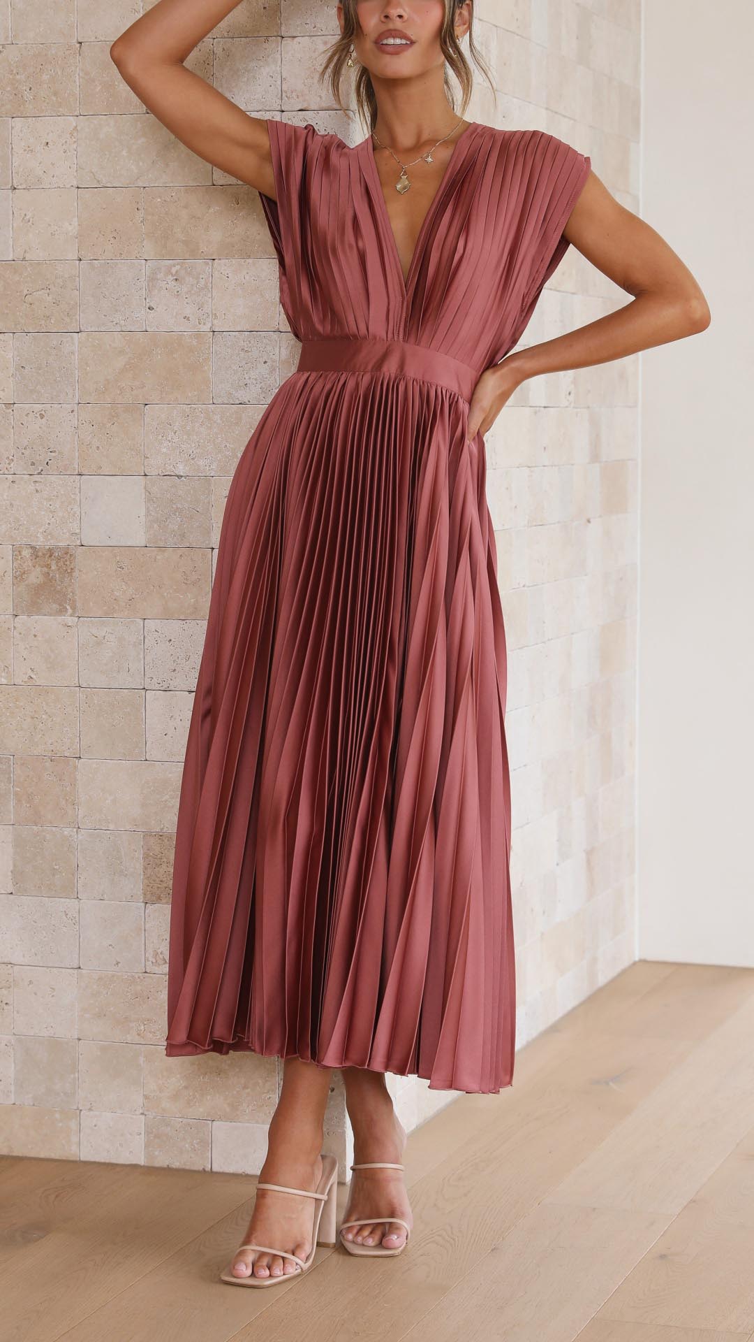 Dettaglio: scollo a V drappeggiato e vita alta di un abito midi plissettato rosa, moda donna elegante.