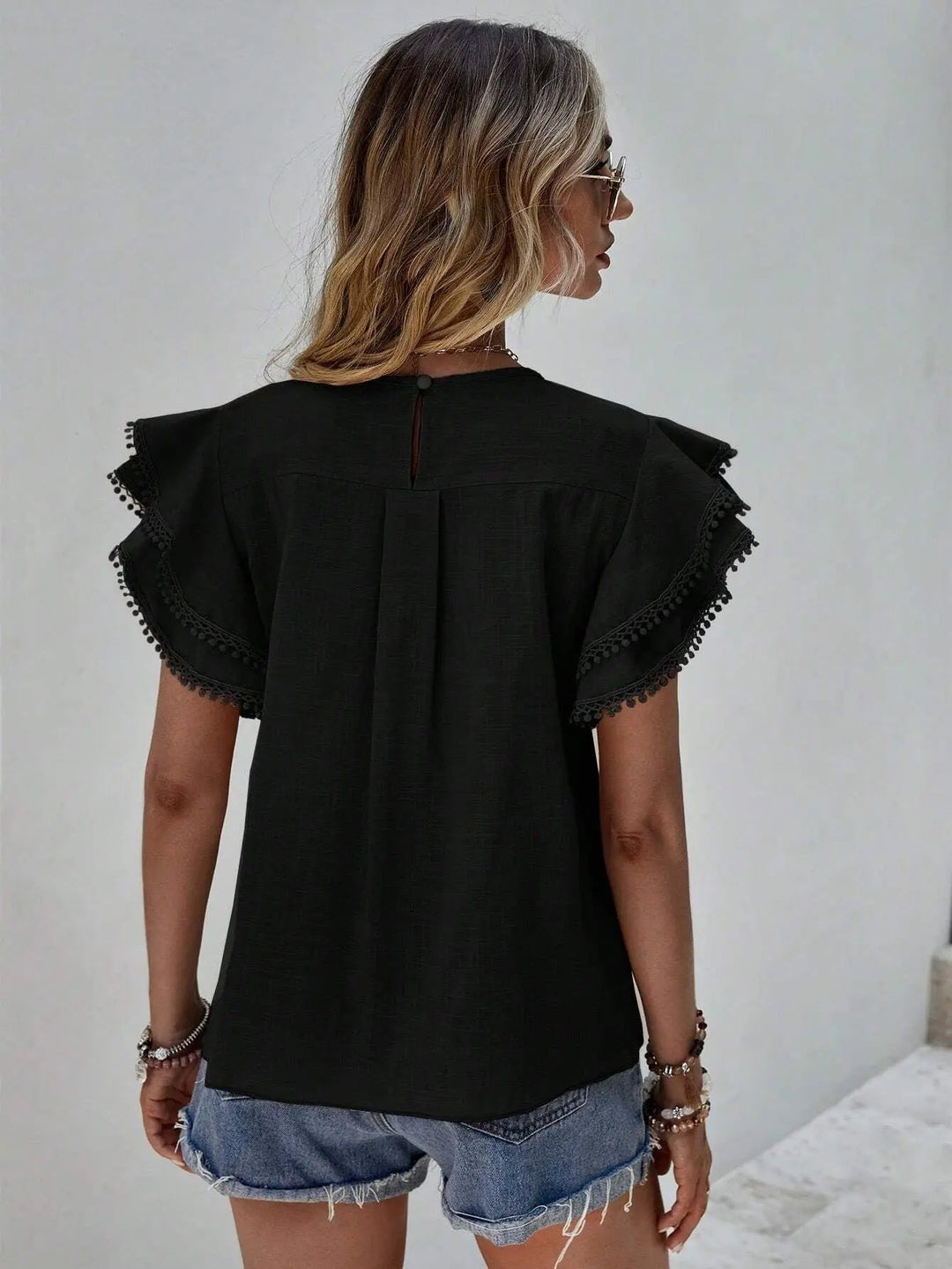 Moda donna primavera estate: elegante top casual con maniche a volant e pompon, vestibilità comoda.