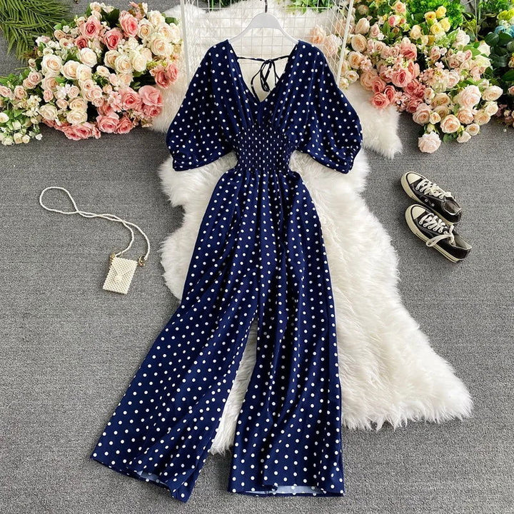 Tuta estiva a pois da donna, mostra vita smock, gamba larga fluida e scollo a V. Outfit versatile primavera/estate.