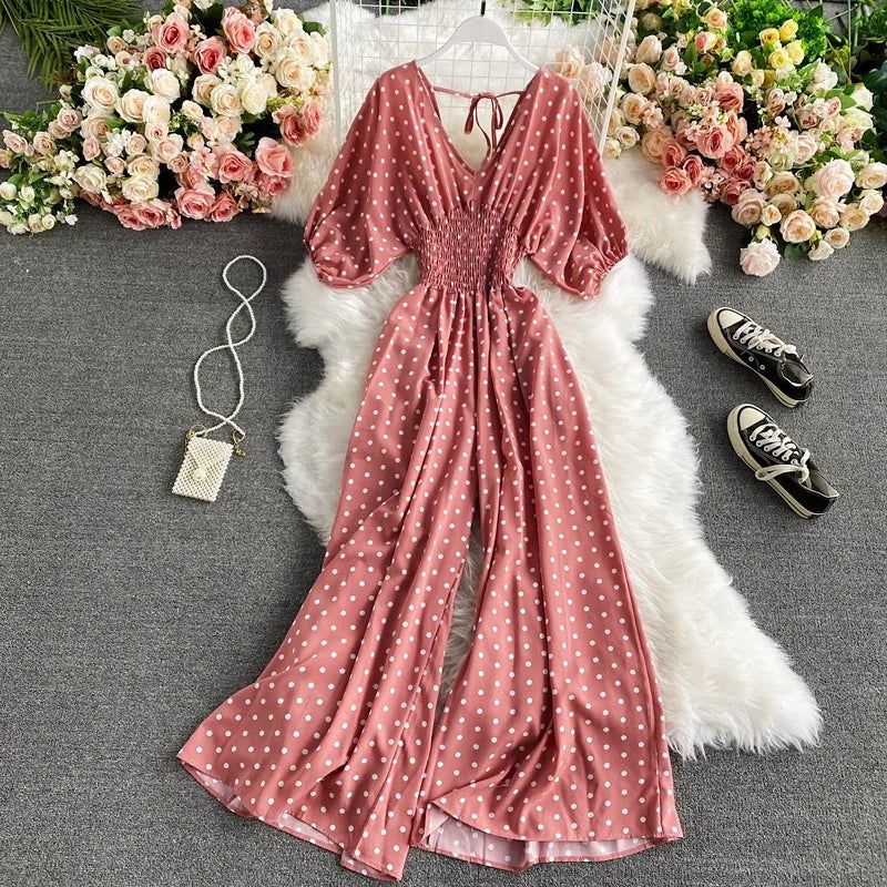 Donna indossa tuta estiva a pois con vita smock. Outfit comodo e chic, gamba larga per il movimento e la moda.