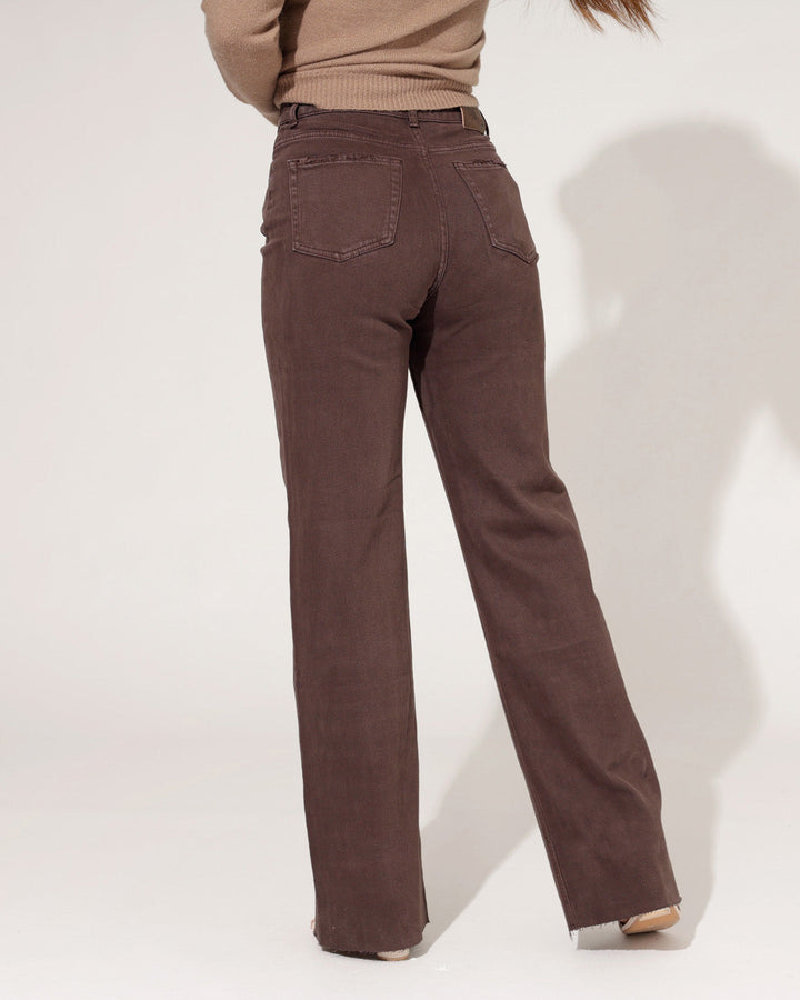 Dettaglio jeans donna marrone scuro, vita alta, con orlo grezzo sfilacciato e gamba ampia.