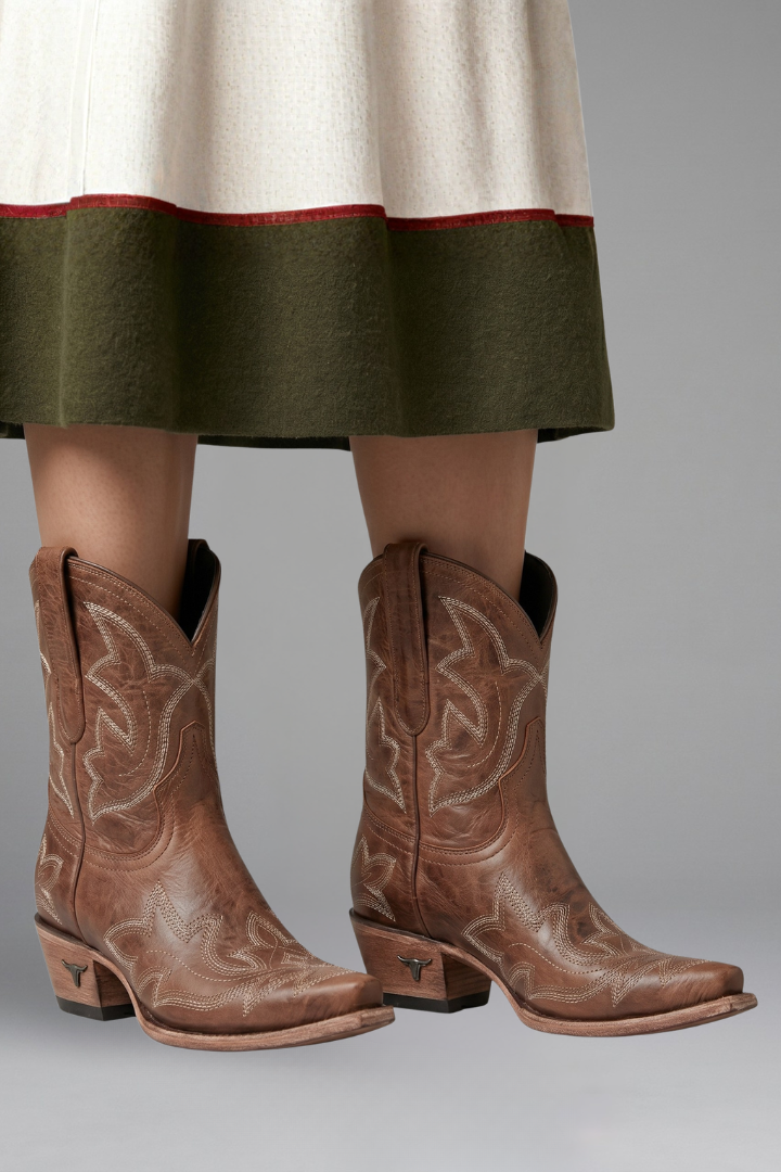 Donna indossa stivali cowboy ricamati con gambale medio e tacco basso. Look western chic per il tempo libero.