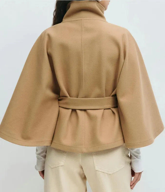 Modella indossa mantella donna con collo alto, cintura e bottoni asimmetrici per stile raffinato.