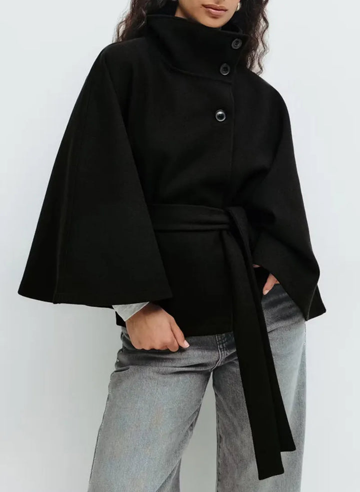 Mantella donna elegante con collo alto, cintura e bottoni asimmetrici. Ideale per un look raffinato.