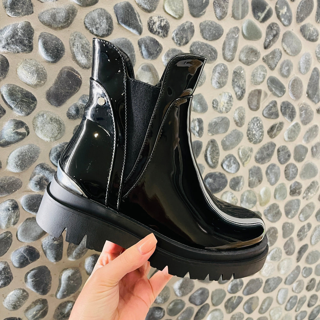 Primo piano stivaletti donna neri lucidi con tacco robusto e zip. Calzature eleganti per l'inverno.