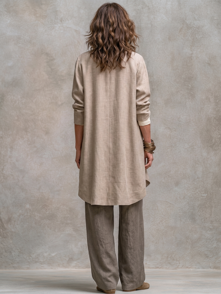 Donna in completo tre pezzi fluido beige-grigio, con cardigan aperto e pantaloni larghi. Look elegante per primavera/autunno.