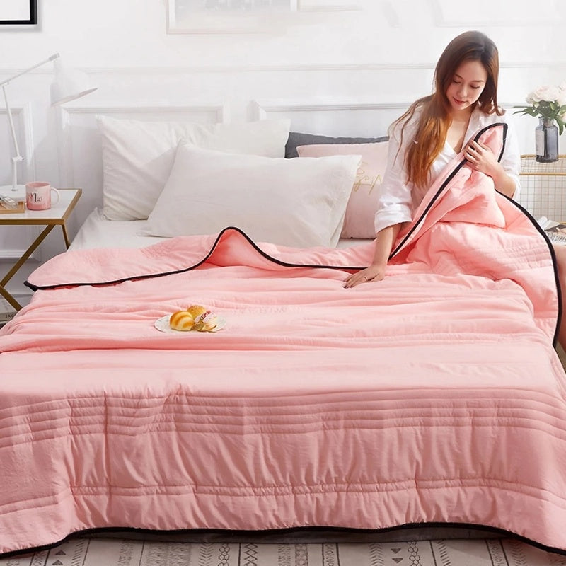 Coperta rinfrescante estiva piegata, leggera e compatta, pronta per l'uso su letto o divano.
