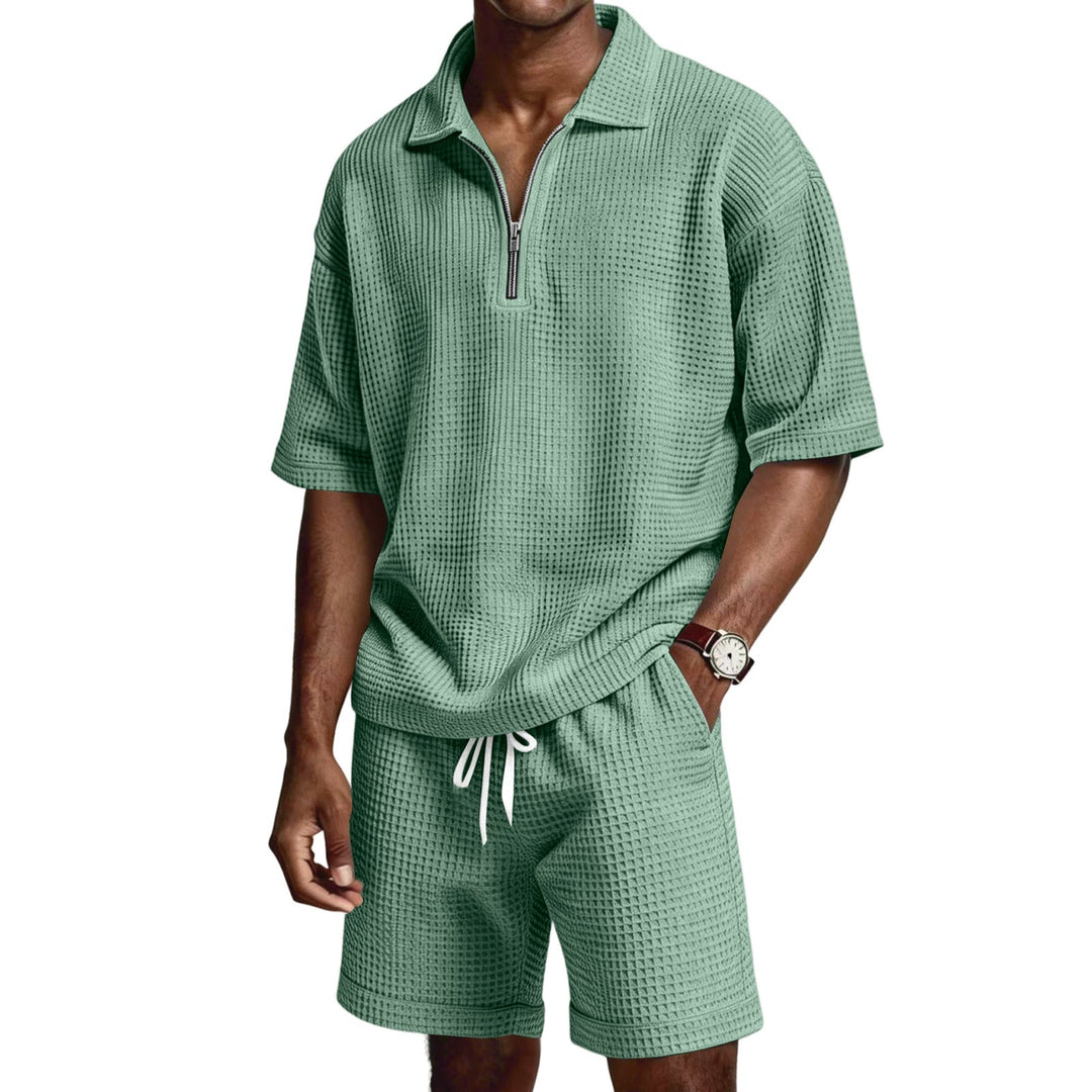 Uomo che indossa completo estivo due pezzi: polo zip e pantaloncini. Perfetto per relax o sport leggero.