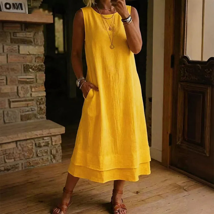 Donna sorridente indossa abito midi estivo smanicato con balza, look comodo e casual chic.