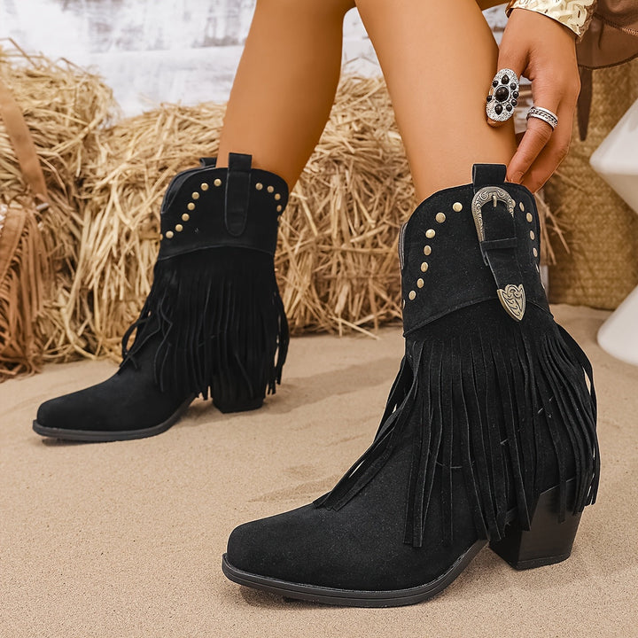 Dettaglio borchie metalliche e frange su stivali cowboy donna. Tacco a blocco, l'anima della moda western.