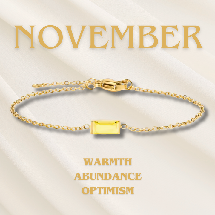 Bracciale da donna placcato oro con charm e pietra di nascita indossato al polso, gioiello raffinato.