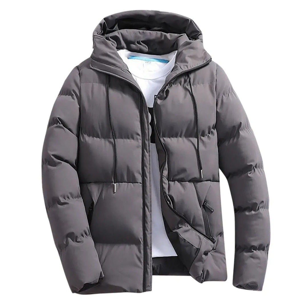 Giacca piumino uomo grigia trapuntata, ideale per l'inverno. Calda, antivento e con cappuccio per stile casual.