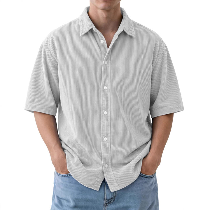 Moda uomo estiva: camicia a maniche corte, vestibilità ampia, texture a coste per un look rilassato.