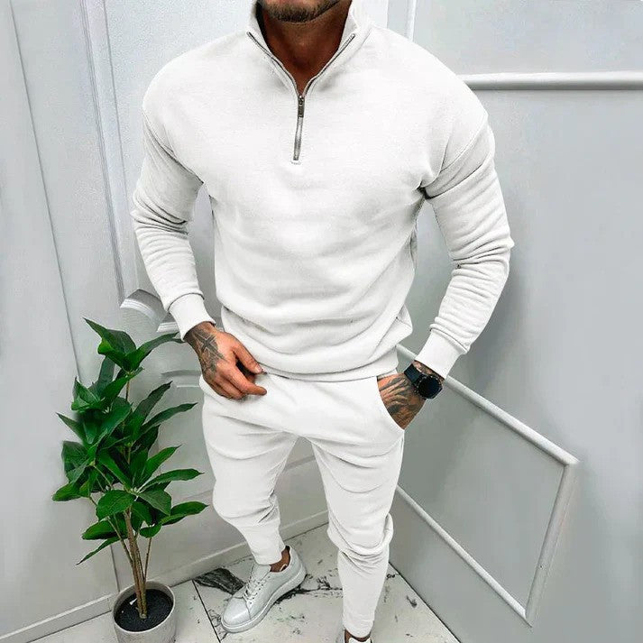 Uomo seduto con completo sportivo athleisure, tuta casual con felpa con cappuccio e pantaloni comodi e versatili.