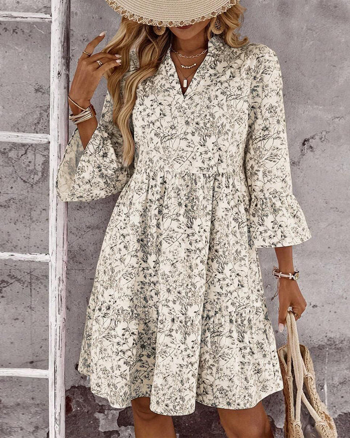 Dettaglio abito donna beige con raffinata stampa floreale, collo alto e maniche a volant. Vestito primaverile.
