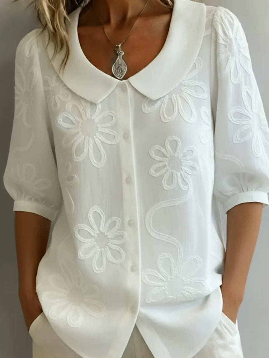 Donna indossa camicetta floreale ricamata. Blusa elegante a vestibilità rilassata, perfetta per la primavera/estate.