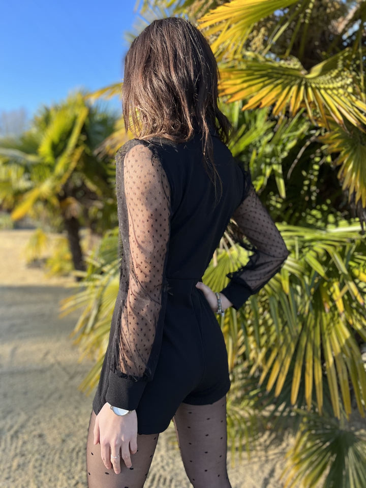 Tuta donna nera raffinata con pizzo floreale e pois delicati, perfetta per un outfit moda sera indimenticabile.