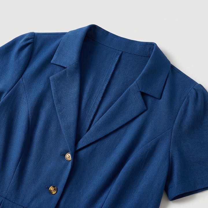 Moda estiva: abito midi plissettato blu con bottoni e scollo a V, che valorizza la silhouette.