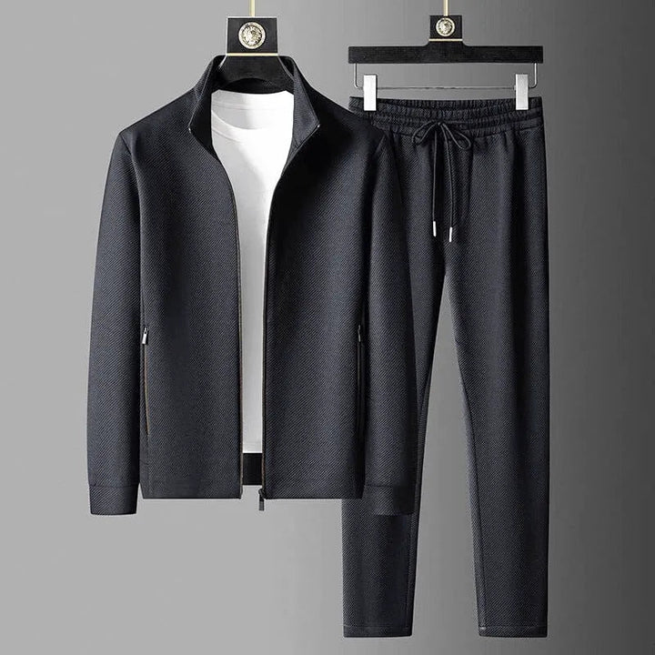 Modello indossa tuta sportiva grigia da uomo, abbigliamento comodo per relax o attività sportiva.