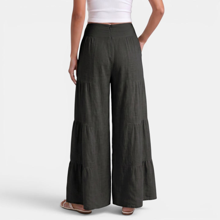 Donna cammina con pantaloni ampi di lino, massima leggerezza, comfort e stile casual chic estivo.