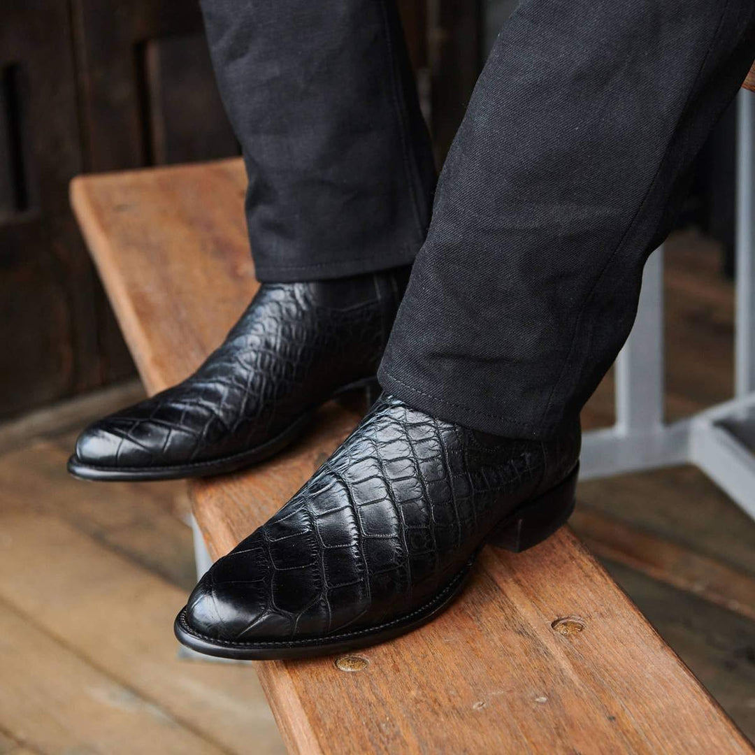 Primo piano stivali cowboy neri da uomo. Dettaglio stampa coccodrillo lucida e punta tonda. Comfort e stile.
