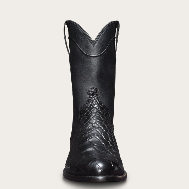 Uomo in piedi con stivali cowboy neri, punta tonda, effetto coccodrillo. Ideali per un look western autentico.