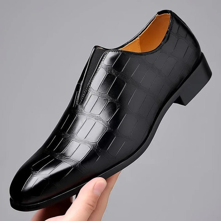 Profilo laterale mocassini uomo eleganti slip-on. Design effetto coccodrillo, lusso e comfort per scarpe da cerimonia nere.