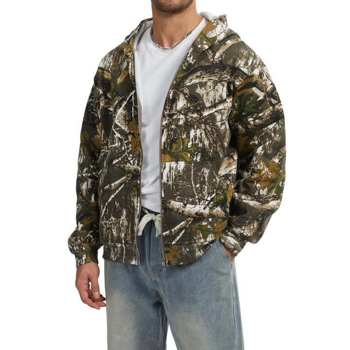 Uomo cammina indossando felpa oversize con zip, cappuccio e stampa fantasia, look casual moderno.