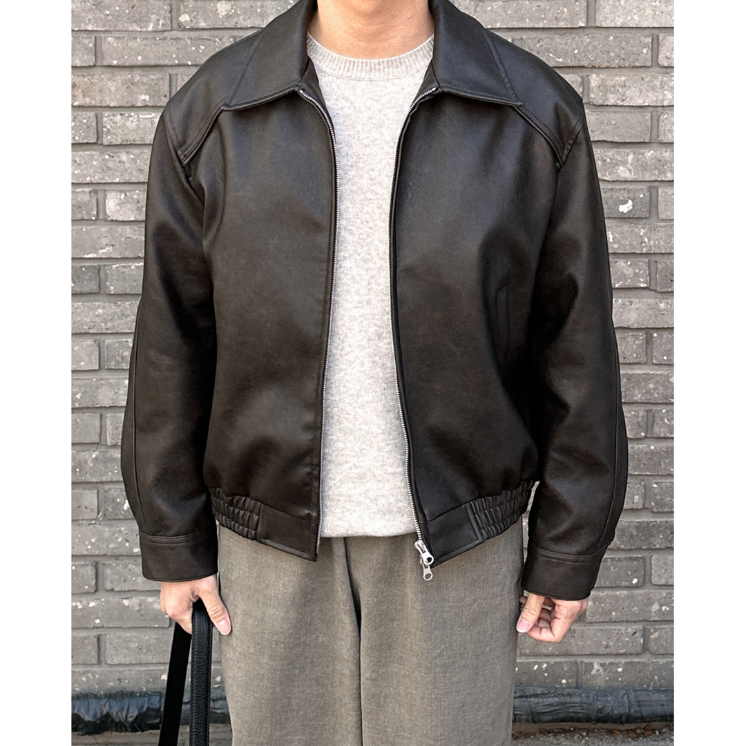 Uomo con giacca bomber nera a collo a punta e zip. Outfit autunnale, casual chic e confortevole.