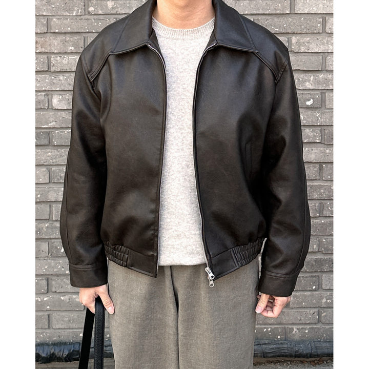 Uomo con giacca bomber nera a collo a punta e zip. Outfit autunnale, casual chic e confortevole.