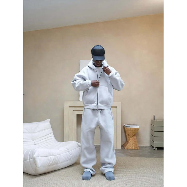 Modello indossa completo tuta uomo oversize, felpa con zip e pantaloni ampi. Stile casual e massima comodità.