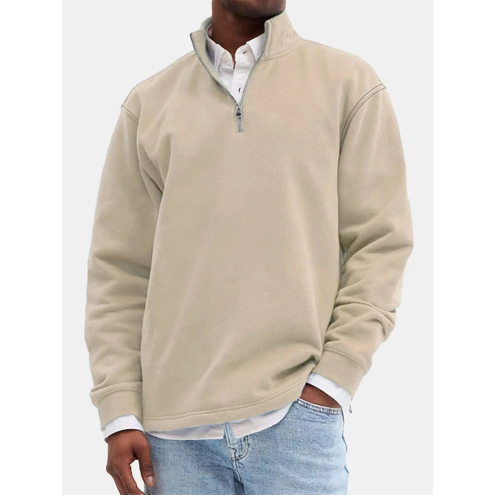 Uomo indossa felpa grigia con zip corta e collo alto, vestibilità rilassata, moda maschile autunno inverno.