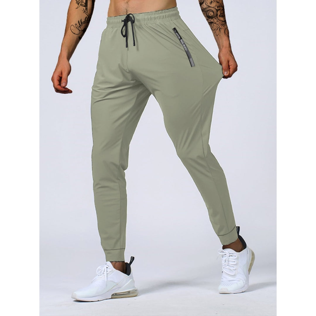 Pantaloni joggers uomo grigio scuro con pratiche tasche zip. Tessuto elasticizzato, perfetti per sport o look casual.