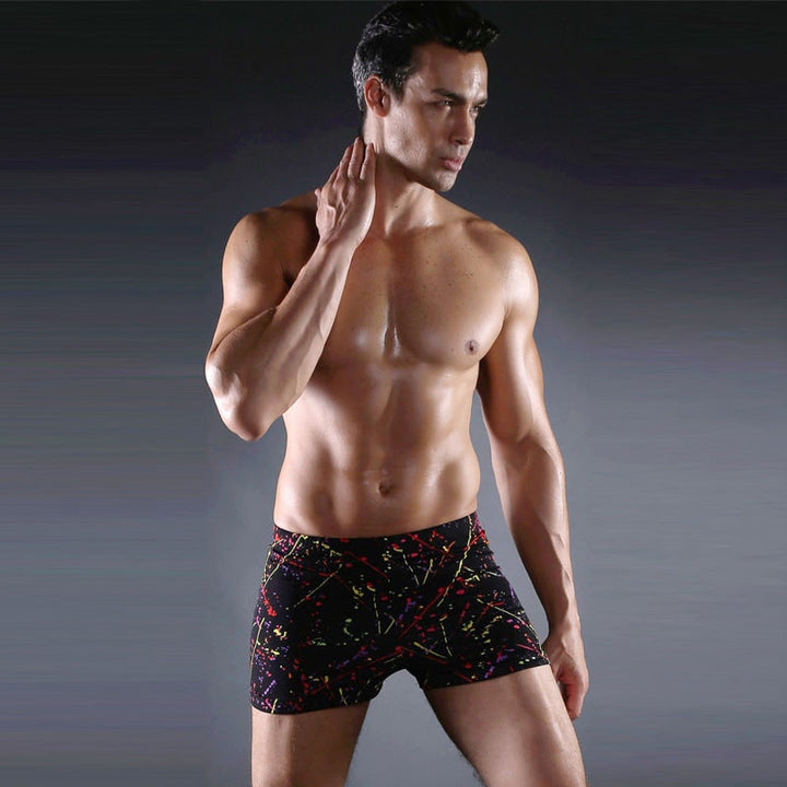 Uomo indossa pantaloncini da bagno sportivi con stampa grafica. Perfetti per la spiaggia, offrono comfort e stile estivo.
