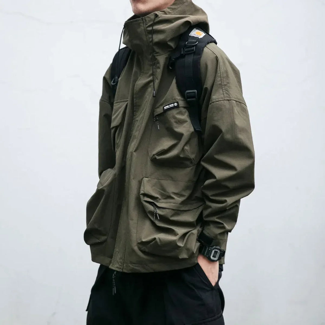 Giacca antivento uomo sportiva con cappuccio, tasche cargo multiuso. Perfetta per attività outdoor e look casual.