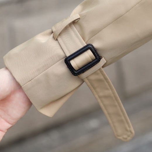 Classico trench uomo doppiopetto, lungo e impermeabile, con cintura. Eleganza senza tempo per ogni occasione.