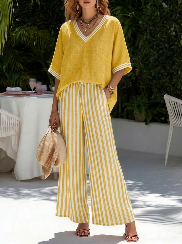 Modella indossa completo donna estivo con top patchwork e pantaloni a righe. Look elegante casual per viaggio.