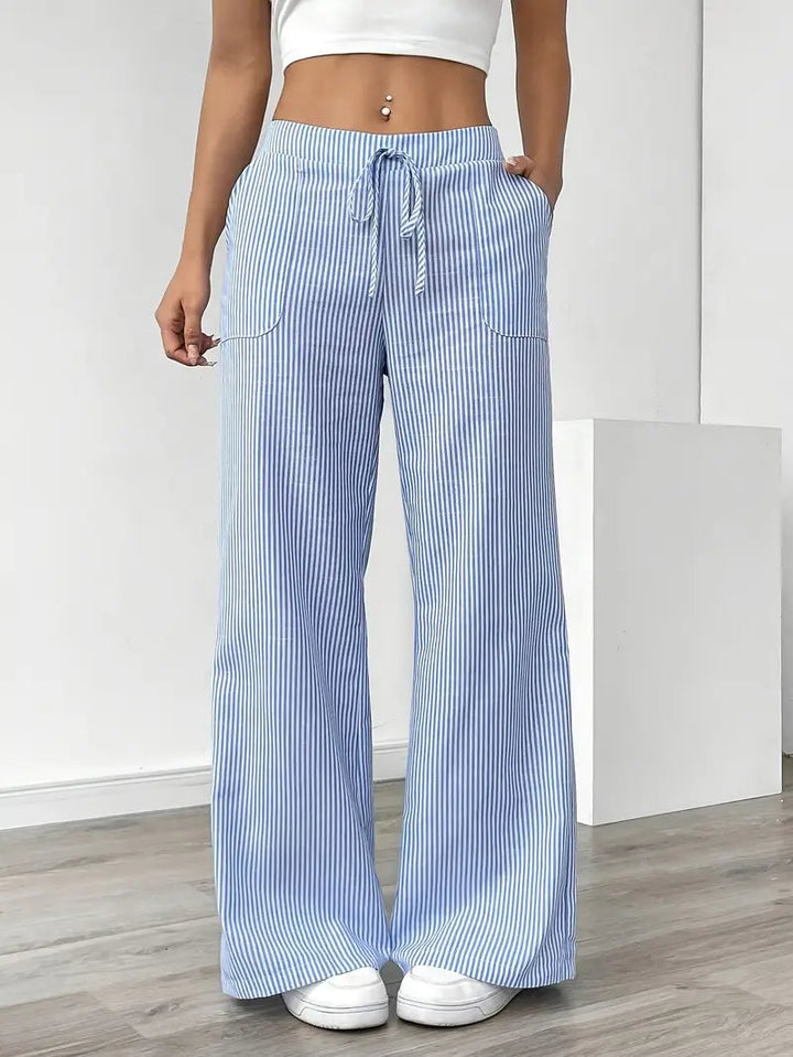Dettaglio tessuto dei pantaloni donna a righe sottili, vita alta, gamba larga. Un capo estivo chic e confortevole.