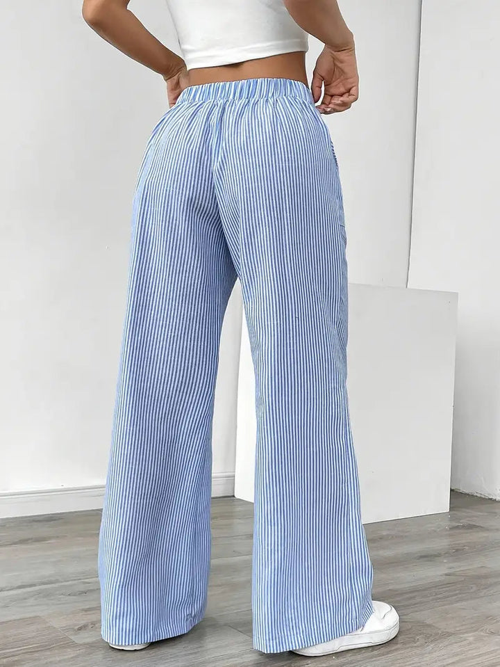 Pantaloni donna a gamba larga a righe, vita alta con sneakers. Look comodo, alla moda e casual chic per l'estate.