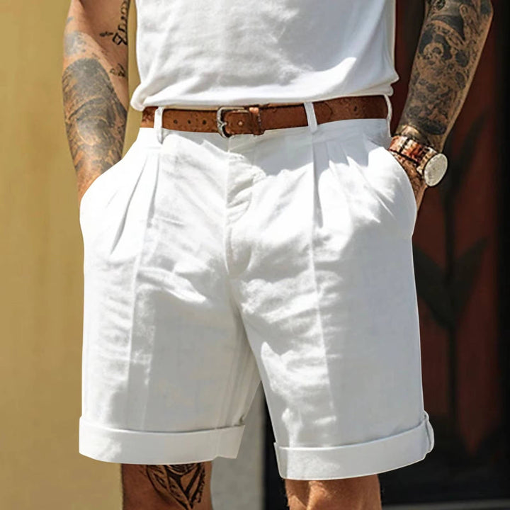 Moda estiva uomo: pantaloncini classici bianchi con vestibilità comoda e pieghe frontali, look sofisticato.