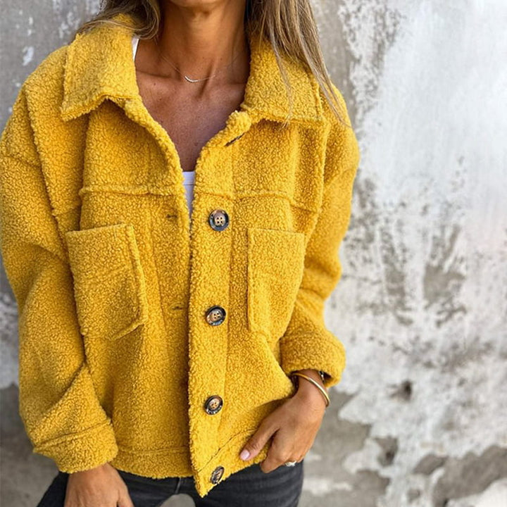 Capospalla corto in pile da donna, con revers, che offre comfort e stile per un abbigliamento elegante e moderno.