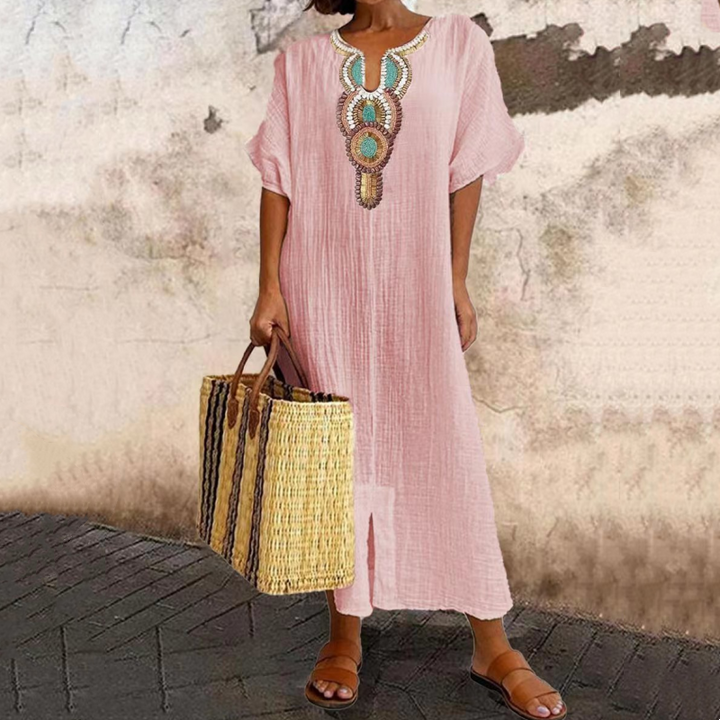 Donna che indossa un ampio vestito maxi bohemien estivo con raffinato ricamo sul collo, vestibilità comoda e stile elegante-casual.