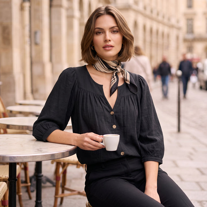 Dettaglio di una blusa da donna, collo a V e maniche 3/4, perfetta per un look moderno ed essenziale.