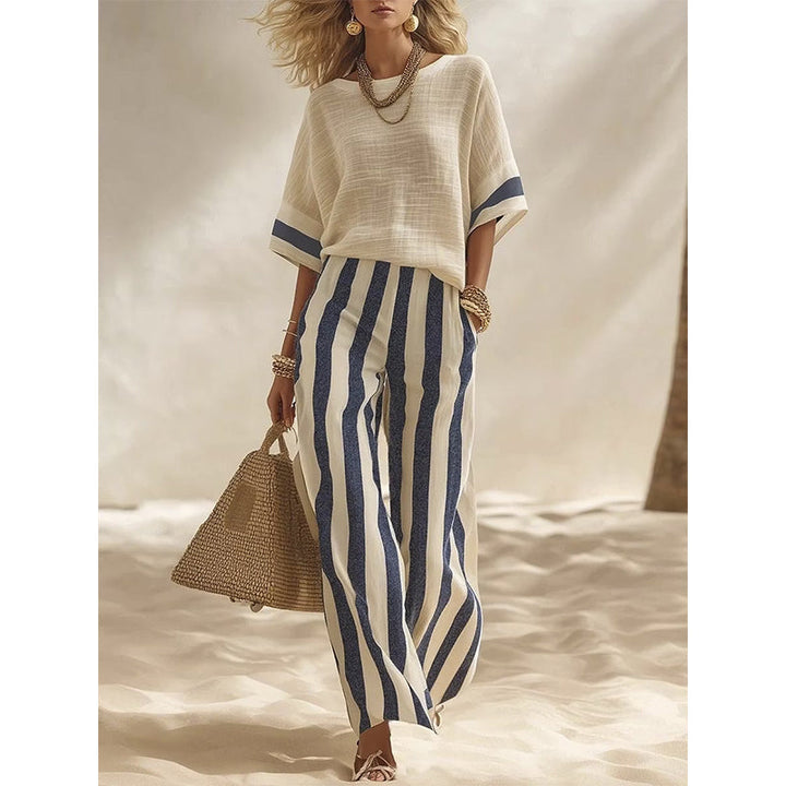 Donna in completo estivo due pezzi, pantaloni larghi a righe e top elegante.
