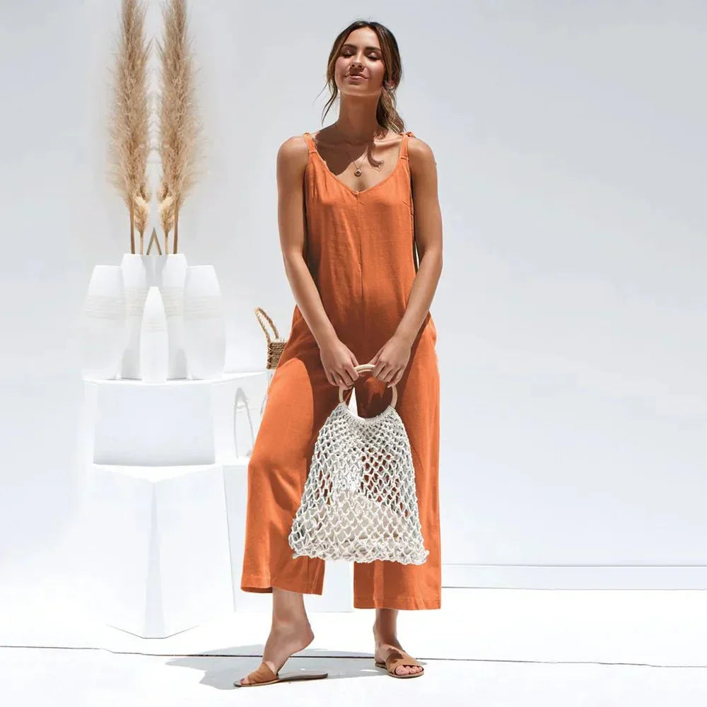 Donna indossa tuta midi nera estiva, senza maniche e scollo a V. Outfit versatile per eleganza casual.