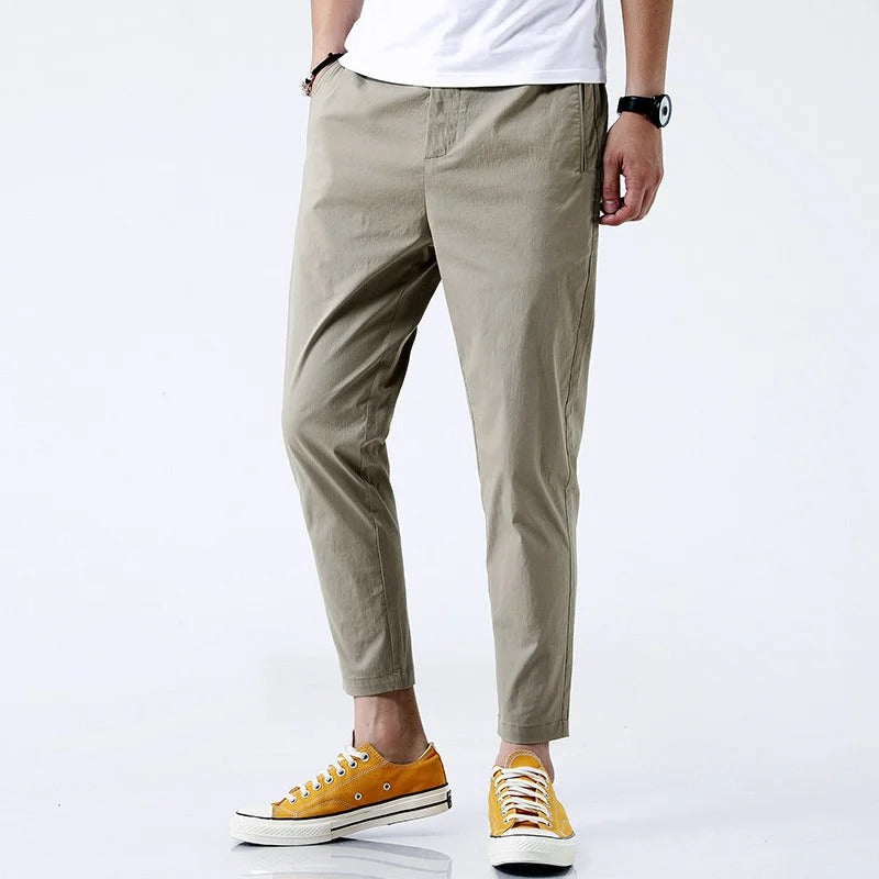 Uomo indossa pantaloni chino straight fit alla caviglia, colore neutro, comfort stretch per eleganza casual e ufficio.