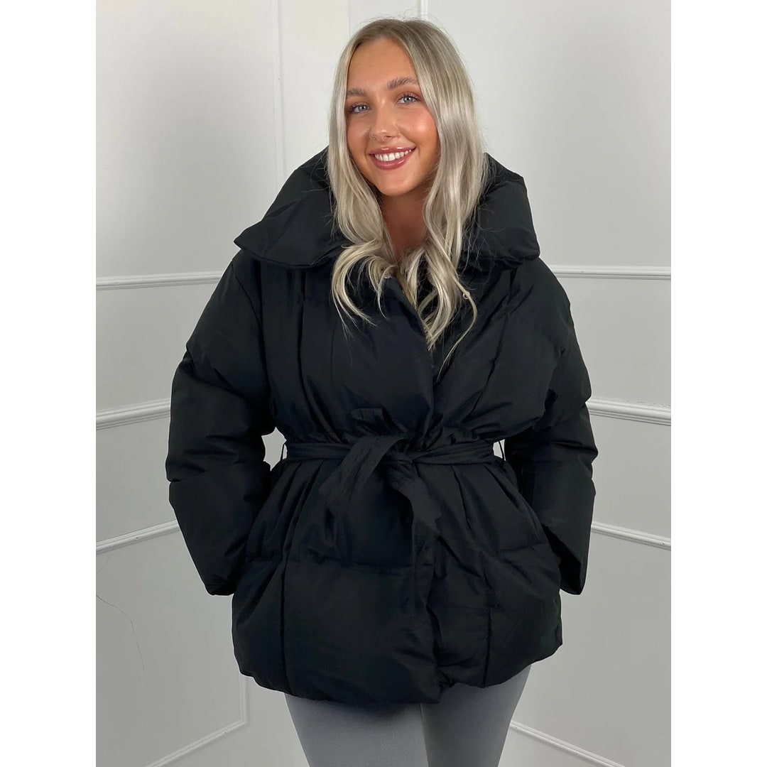 Giacca puffer donna, vista laterale, oversize, con cinto e collo alto. Silhouette elegante per l'inverno.