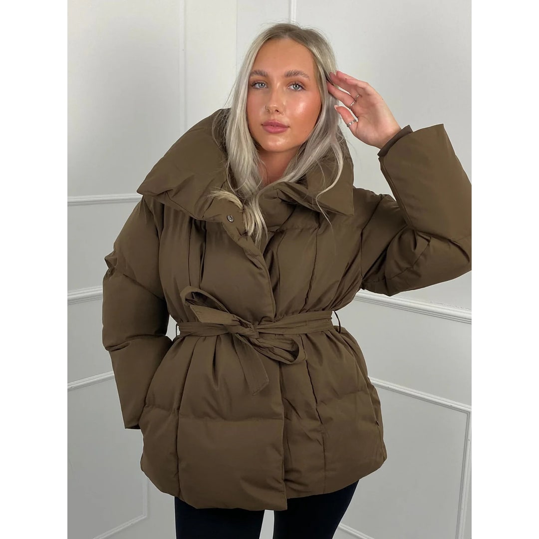 Donna con elegante giacca puffer oversize. Cinto e collo alto per un look invernale sofisticato e confortevole.